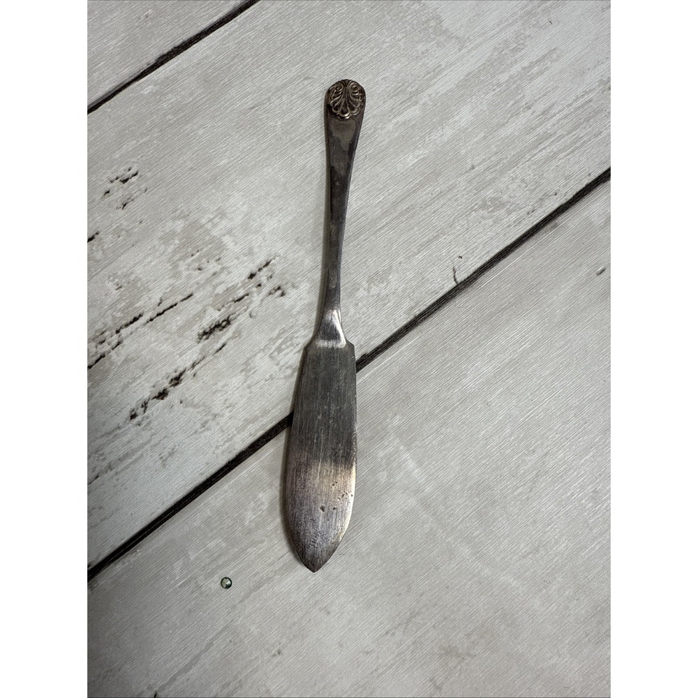 A silver-plated butter spreader with shell design on the handle. Made In England